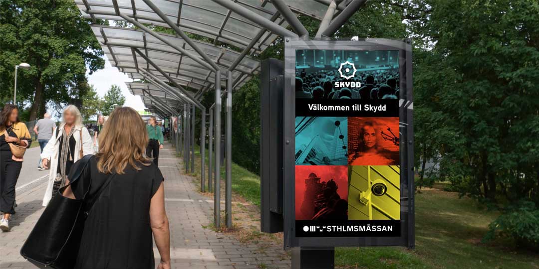 En kvinna som går förbi en digitalskylt där en "Välkommen till Skydd" skylt syns